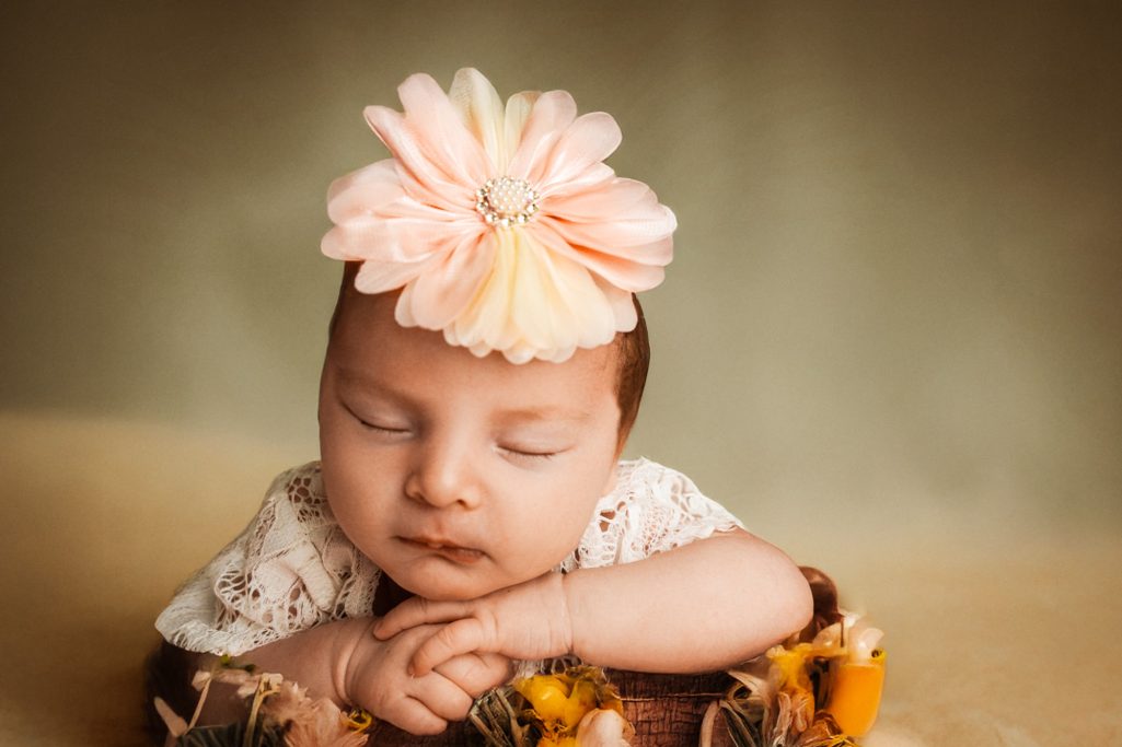 Süßes Baby mit Blumenkopfband schläft auf gestellten Sonnenblumen.